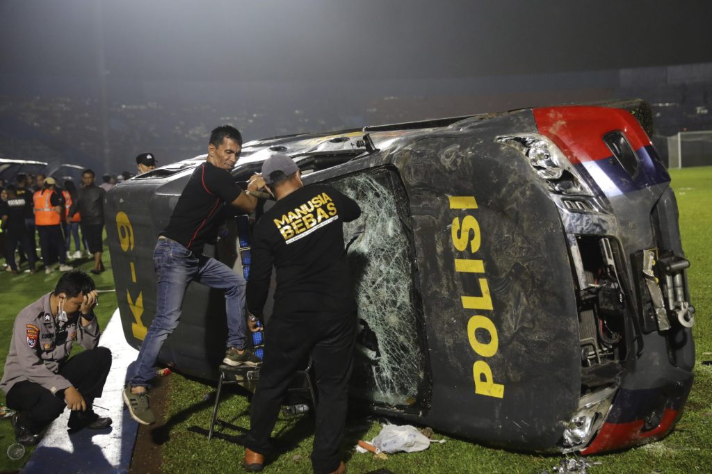 Officers examine a damaged police vehicle following a clash between supporters of two Indonesian soccer teams at Kanjuruhan Stadium in Malang, Indonesia.