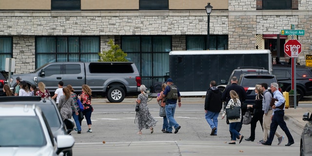 Police evacuate people from buildings near the Hampton Inn in Dearborn, Michigan on Oct. 6, 2022. Police negotiated with a suspected gunman inside the suburban Detroit hotel after reports of gunfire led to evacuations.