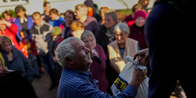 Locals receive food given by Ukrainian volunteers in the recently retaken village of Boguslavka village, east Ukraine, Friday, Oct. 7, 2022.