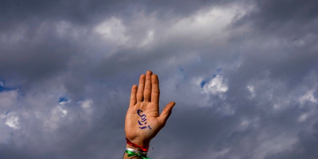 An Iranian national raises their hand with a message that reads in Farsi, "Liberty," during a protest against the death of Iranian Mahsa Amini, in front of the Universidad de Chile building in Santiago, Chile, Friday, Oct. 7, 2022.