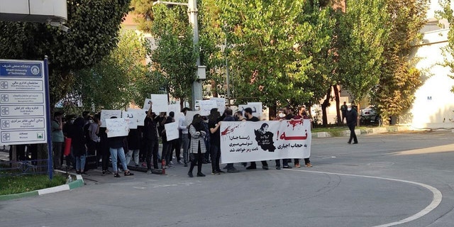 In this photo taken by an individual not employed by the Associated Press and obtained by the AP outside Iran shows students of the Sharif University of Technology attend a protest sparked by the death in September of 22-year-old Mahsa Amini in the custody of the country's morality police, in Tehran, Friday, Oct. 7, 2022. The banner says: "No to mandatory hijab" and "Dear Zhina, (Amini's nickname), you won't die, your name will become a symbol."