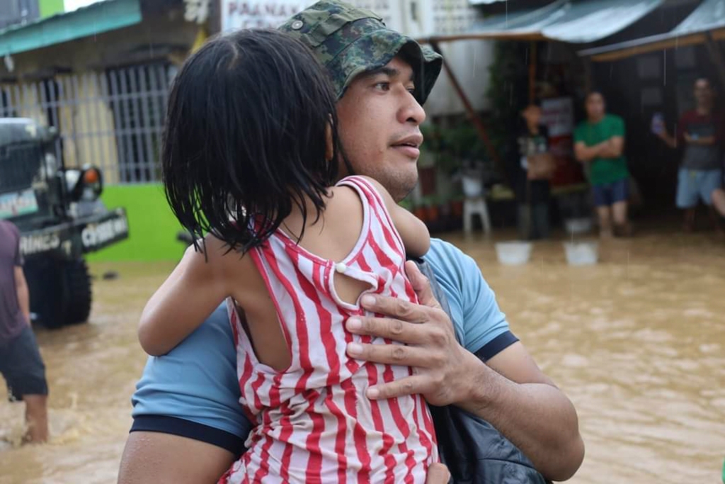 A rescuer carries a child from the flood waters after the tropical storm hit the southern part of the Philippines.
