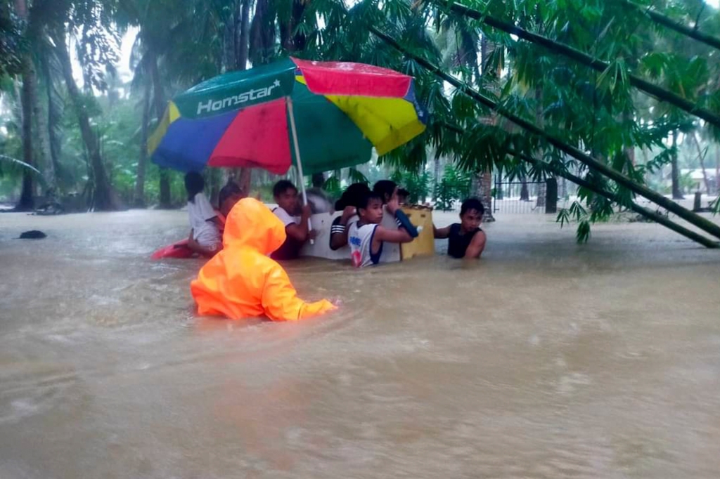 People stranded by the flood waters use a refrigerator to float to safety.