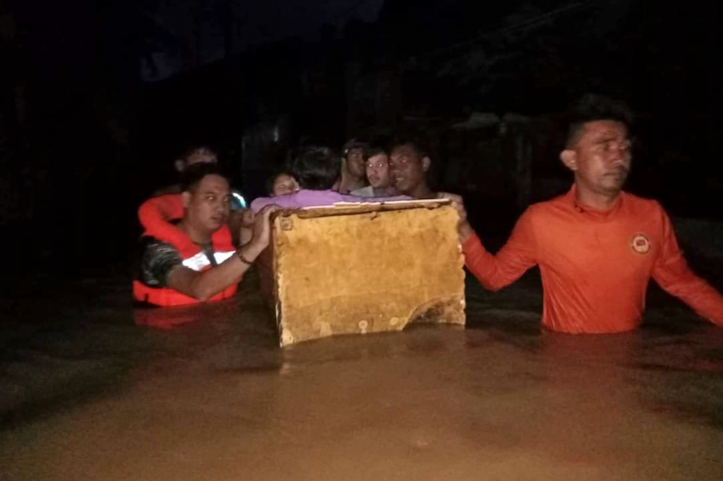 Members of the Coast Guard help evacuate residents, sitting in makeshift raft, through the floodwaters.