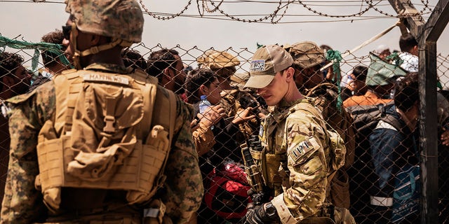 In a photo shared by the U.S. Marine Corps, U.S. service members provide assistance during an evacuation at Hamid Karzai International Airport, Kabul, Afghanistan, on Sunday, Aug. 22, 2021. 