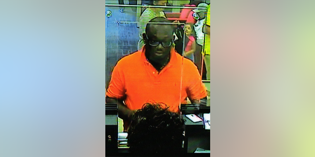 Babtunde Popoola at a bank teller window. Popoola was one of the scammers prosecuted for his role in defrauding Donald Griffith and others.