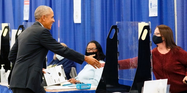 Former President Barack Obama shakes hands with a poll worker before casting his ballot at an early voting site Monday, Oct. 17, 2022, in Chicago. (AP Photo/Charles Rex Arbogast)