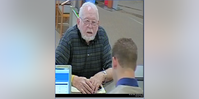 Donald Griffith depositing money to send to the scammers at a bank teller window. 