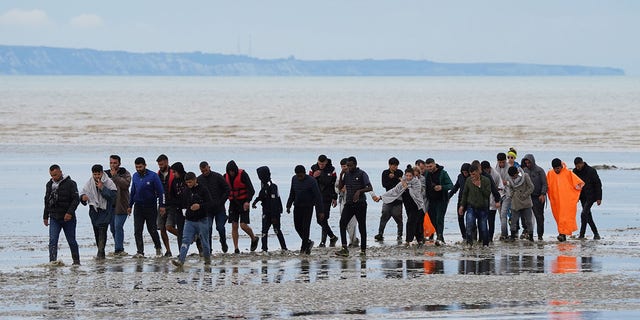 A group of people, thought to be migrants, walk ashore in Dungeness, Kent, following a small boat incident in the Channel. Picture date: Thursday August 25, 2022. 