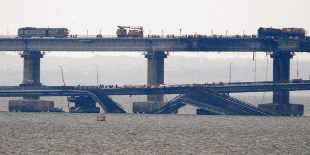 Workers restore the railway tracks on the Kerch bridge that links Crimea to Russia, near Kerch, on Oct. 9, 2022, a day after it was damaged by a blast.