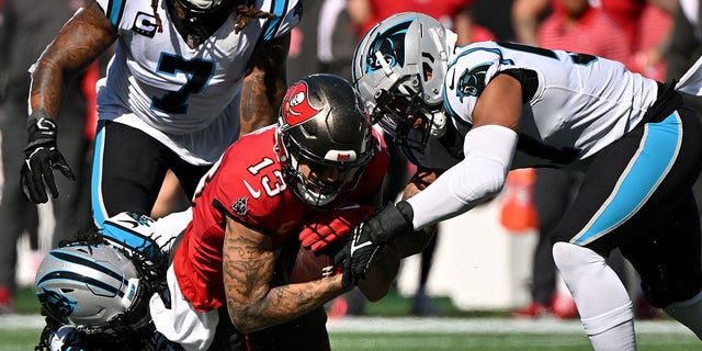 Damien Wilson and Donte Jackson of the Panthers tackle Mike Evans of the Tampa Bay Buccaneers on Oct. 23, 2022, in Charlotte, North Carolina.