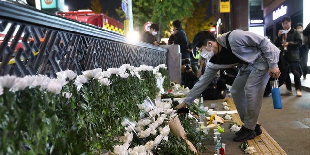 A man lays flowers as he mourns at the street of a deadly stampede during a Halloween festival on October 30, 2022 in Seoul, South Korea. (Photo by Chung Sung-Jun/Getty Images)