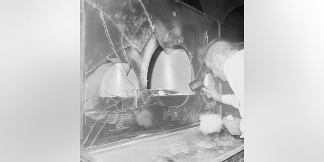 Policeman dusts for fingerprints on a case broken into at the American Museum of Natural History during a jewelry robbery.