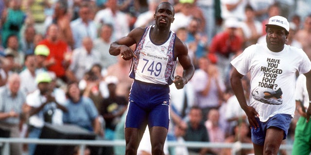 Great Britain's Derek Redmond, left, limps around the track toward the finish line after tearing his hamstring as his dad Jim races after him to offer help and consolation.