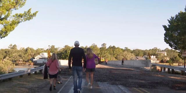 From left, A.J. McCullough of Sunset Beach, NC, mother of bride Monroe McCullough, an unidentified man, and  Mary Lord of Ft. Worth, Texas, mother of groom Eric Lord walk off the island on Saturday, Oct. 1, 2022 in Pawleys Island, S.C.