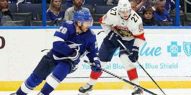 Florida Panthers center Eetu Luostarinen (27) works around Tampa Bay Lightning defenseman Ian Cole (28) during the third period of an NHL preseason game Saturday, Oct. 8, 2022, in Tampa, Fla.