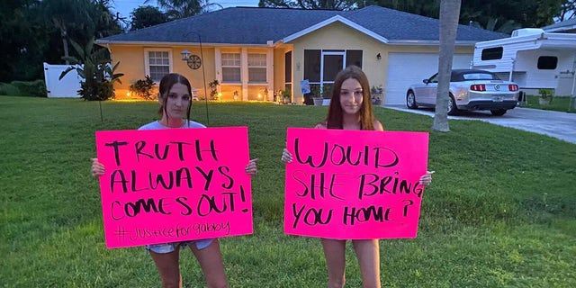 Protesters carry signs to the home of Brian Laundrie in September 2021, urging him to speak with police.