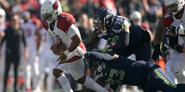 Arizona Cardinals quarterback Kyler Murray, left, runs against Seattle Seahawks defensive end Shelby Harris (93) and defensive tackle Quinton Jefferson (77) during the first half of an NFL football game in Seattle, Sunday, Oct. 16, 2022. 