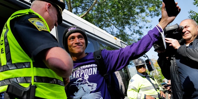 Carlos, a Venezuelan migrant, waves to volunteers before boarding a bus to the Vineyard Haven ferry terminal outside of St. Andrew's Parish House.