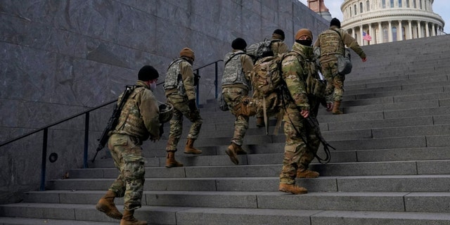 FILE - National Guard members take a staircase toward the U.S. Capitol building before a rehearsal for President-elect Joe Biden's Presidential Inauguration in Washington, Jan. 18, 2021. 