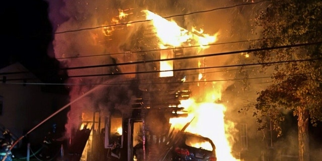 A firefighter is seen battling a large fire at a barn in Wappinger, N.Y. after a 17-year-old driver crashed into the building, causing it to erupt into flames.