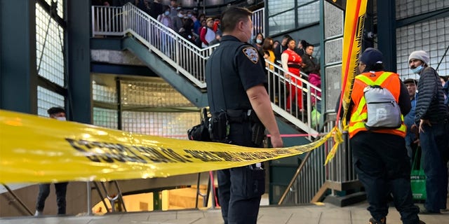 An NYPD officer stands behind caution tape. 