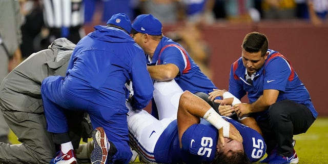 New York Giants center Nick Gates (65) lies on the field as members of the team medical staff tend to him Sept. 16, 2021, in Landover, Md. 