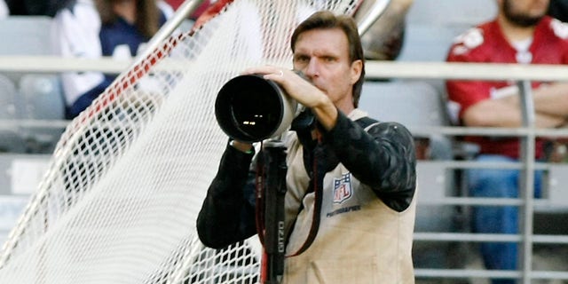 Former MLB pitcher Randy Johnson photographs an NFL game between the Dallas Cowboys and Arizona Cardinals in Glendale, Arizona, Dec. 4, 2011.