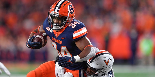 Syracuse running back Sean Tucker (34) is tackled by Virginia linebacker Chico Bennett Jr. (15) during the first half of an NCAA college football game Friday, Sept. 23, 2022, in Syracuse, N.Y.