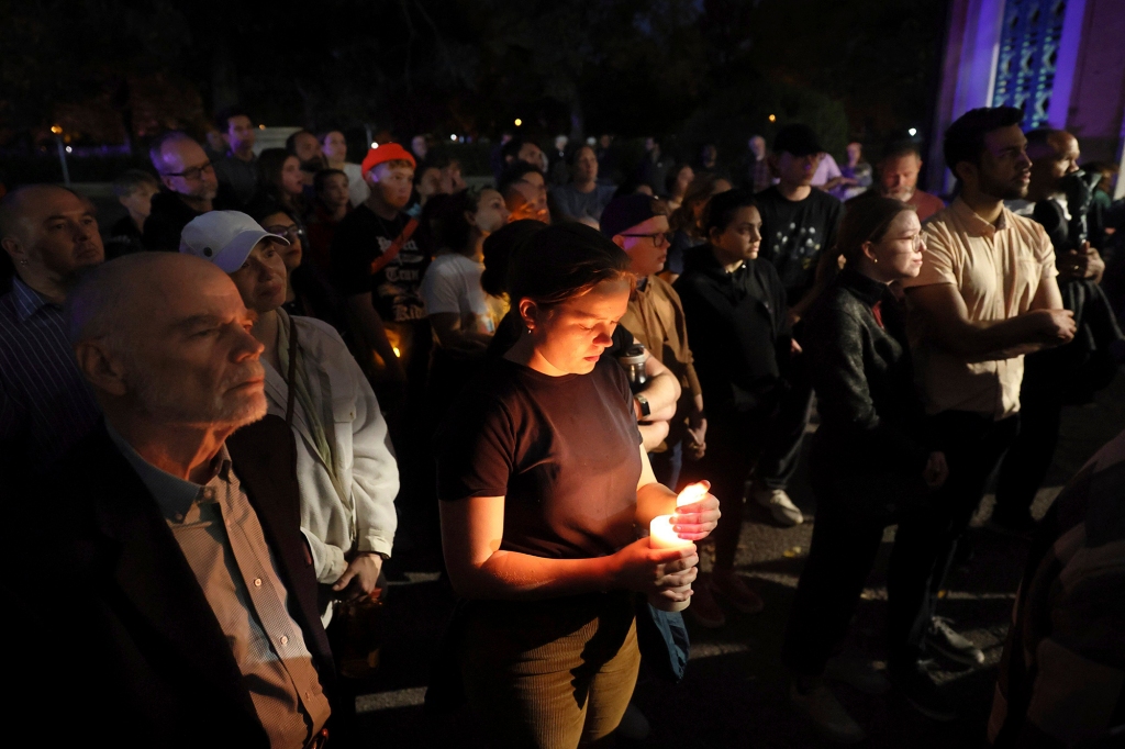 Marie Crane, center, holds a candle during a vigil in Tower Grove Park for the victims of a school shooting at Central Visual & Performing Arts High School in St. Louis on Oct. 24, 2022.