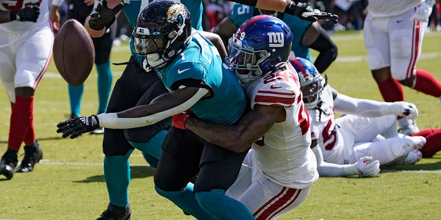 Jacksonville Jaguars running back Travis Etienne Jr., #1, fumbles when he gets hit by New York Giants safety Xavier McKinney, #29, during the first half of an NFL football game Sunday, Oct. 23, 2022, in Jacksonville, Florida.