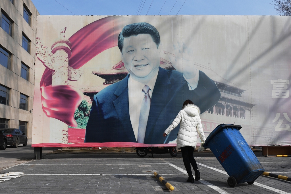 a faded propaganda billboard featuring an image of China's President Xi Jinping, in a car park in Beijing on March 19, 2018.