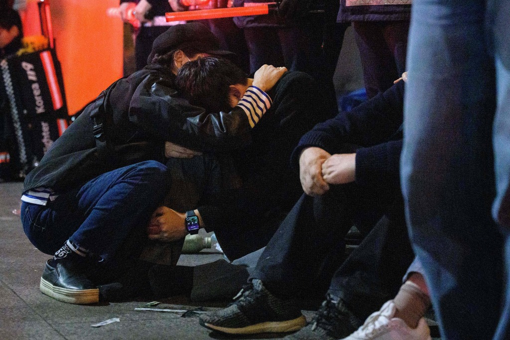 People comfort each other after a stampede at a packed Halloween event in central Seoul.