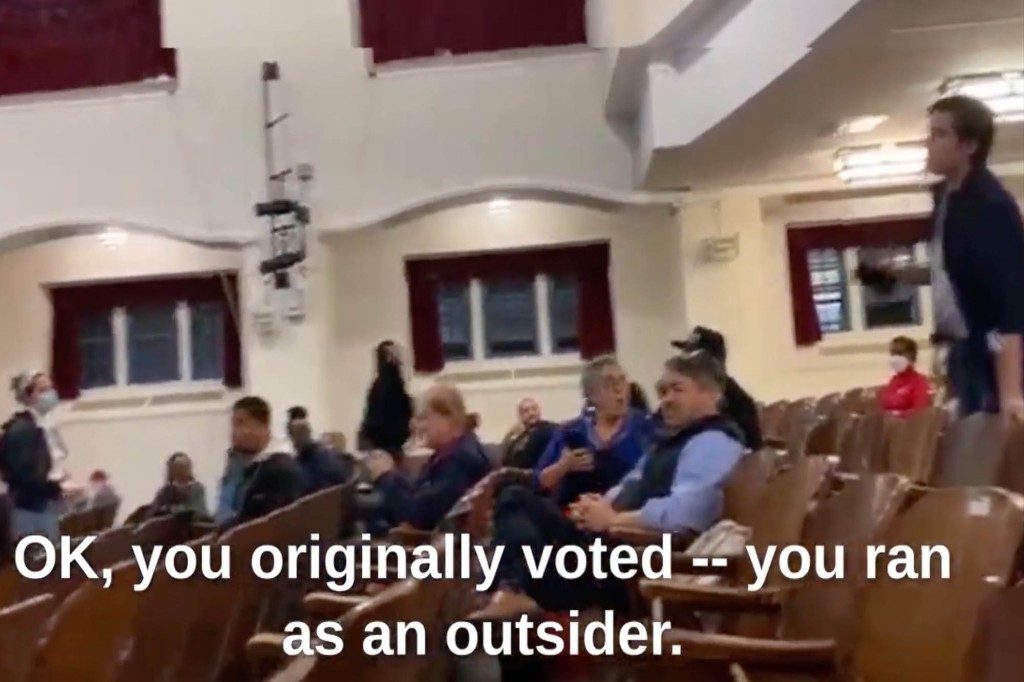 A protester heckles Alexandria Ocasio-Cortez during a town hall event.