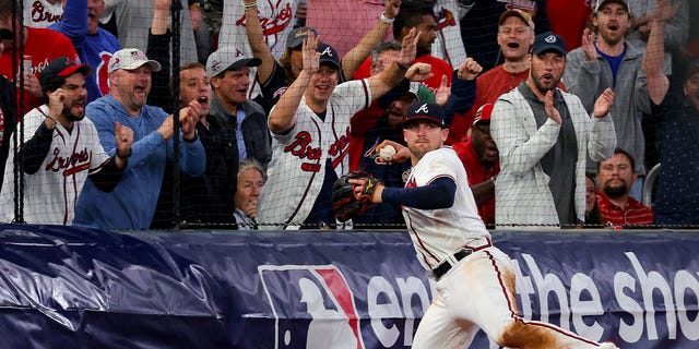 Austin Riley #27 of the Atlanta Braves throws the ball after making a catch against the Philadelphia Phillies during the eighth inning in game two of the National League Division Series at Truist Park on October 12, 2022 in Atlanta, Georgia.