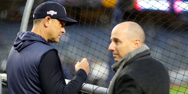 Manager Aaron Boone of the New York Yankees, left, watches batting practice as general manager Brian Cashman looks on prior to Game 4 of the ALCS against the Houston Astros Oct. 17, 2019, in the Bronx borough of New York City. 