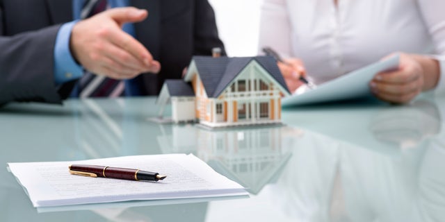 FILE - A banker and a homebuyer discussing a real estate purchase.