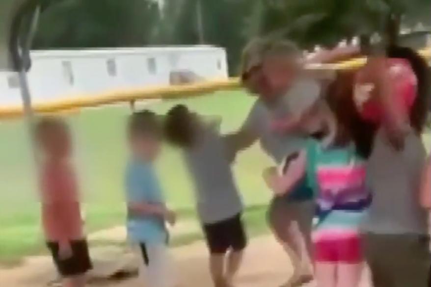 The footage appears to show the worker yanking a child by the arm.