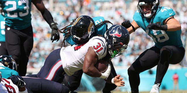 Dameon Pierce #31 of the Houston Texans is tackled by Rayshawn Jenkins #2 of the Jacksonville Jaguars during the second half at TIAA Bank Field on October 09, 2022 in Jacksonville, Florida.