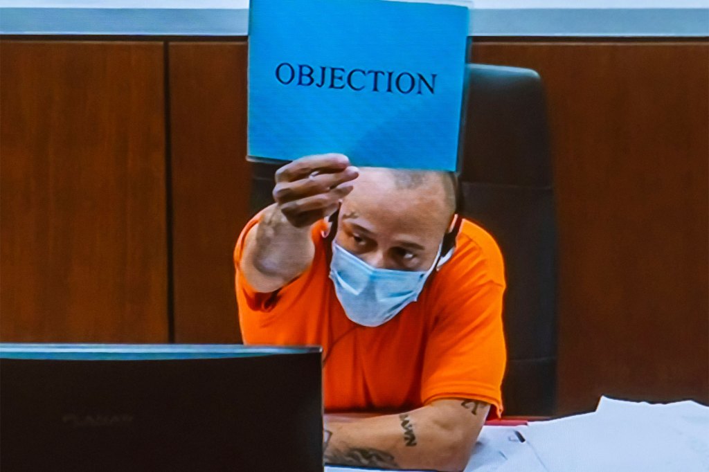 Darrell Brooks holds up a blue sign with the word "objection" on it. 