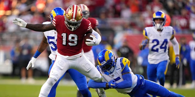 Wide receiver Deebo Samuel #19 of the San Francisco 49ers rushes for a touchdown as he breaks a tackle by cornerback Jalen Ramsey #5 of the Los Angeles Rams during the second quarter at Levi's Stadium on October 03, 2022 in Santa Clara, California.