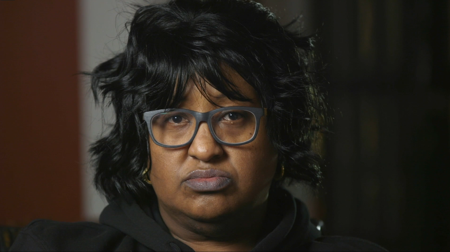 Close-up of Eleanor Morgan, facing the camera, in dark-framed glasses and a black top.