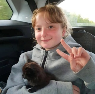 12-year-old Lola poses in a car with a pet cat. 