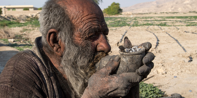 Amou Haji smokes from his water pipe near the village of Dezhgah, Iran, on Dec. 28, 2018.