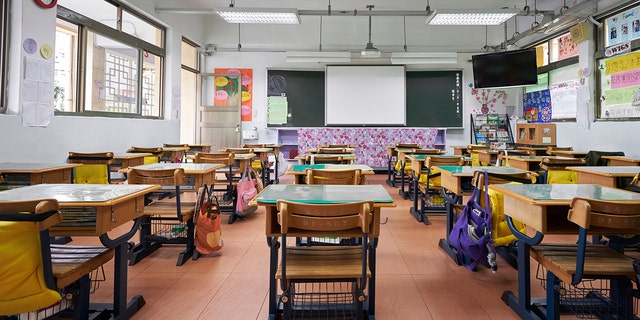 Row of empty desks in front of whiteboard. Interior of classroom in school.