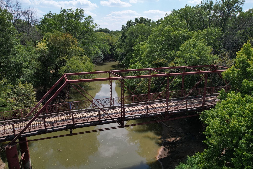An iron truss bridge over a brown river. 