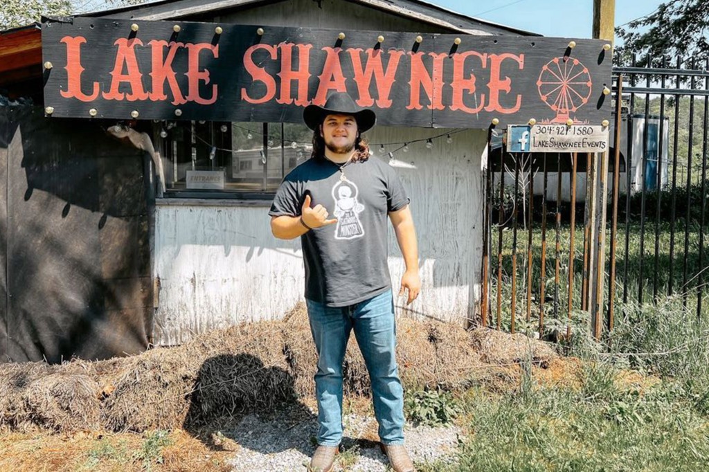 Kalani Smith, ghost hunter, wearing a cowbly hat smiling in front of a shed. 