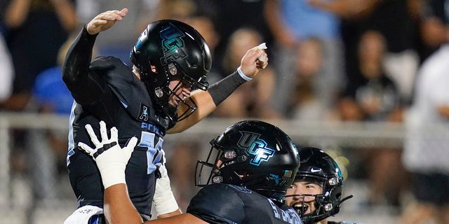 Central Florida quarterback John Rhys Plumlee, left, celebrates a 1-yard touchdown run against Temple with offensive lineman Samuel Jackson (73) and wide receiver Stephen Martin (47) during the first half of an NCAA college football game Thursday, Oct. 13, 2022, in Orlando, Fla.