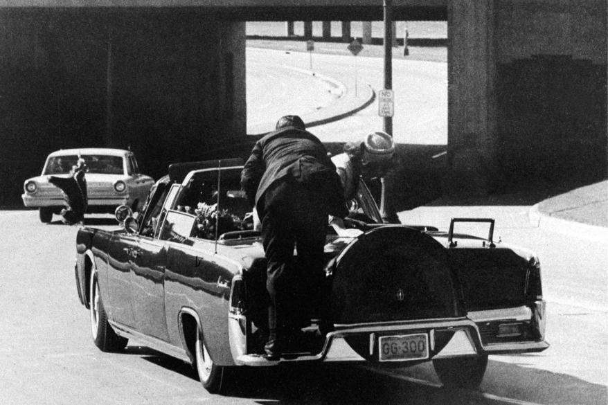A picture of A picture of former President John F. Kennedy moments after his assassination, with Mrs. Kennedy leaving over his body.