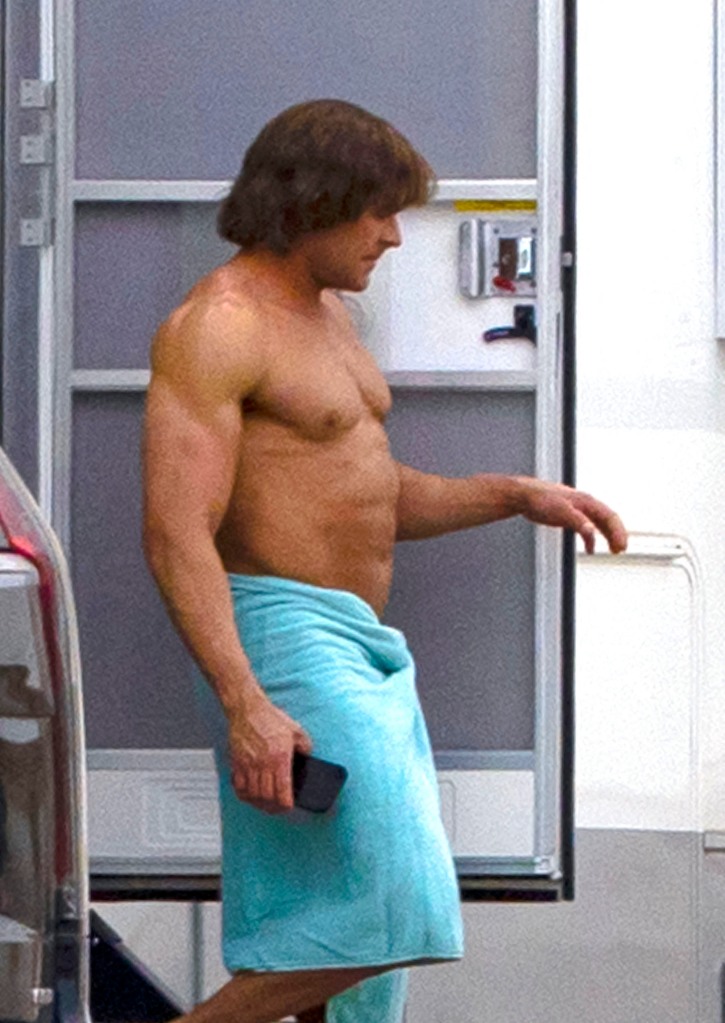 Sporting a six pack and a deep bronze tan, the musclebound actor looked worlds away from his fresh-faced  High School Musical  days as he stepped out of his trailer on set in Louisiana. He was completely unrecognizable after undergoing a dramatic body transformation for the new role, wearing a brown wig and wrapping his taut torso in a skimpy blue towel. At one point, he could be seen adjusting his privates as he prepared to film swimming scenes for the hotly-anticipated movie, which features an all-star cast including Harris Dickinson, Holt McCallany, Jeremy Allen White and Maura Tierney. Based on the true story of the Von Erichs, the film follows the rise and fall of the family dynasty of wrestlers who made a huge impact on the sport from the 1960s to the present day. In between scenes, 35-year-old Efron sipped from an aluminum bottle of Rain, a plastic free natural spring water.
